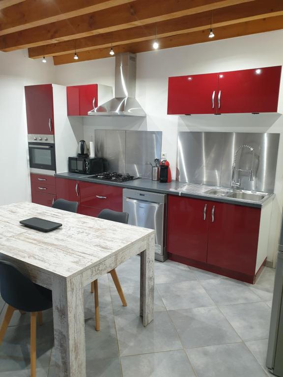 uma cozinha com armários vermelhos e uma mesa de madeira em Gîte l'olivier em Mézoargues