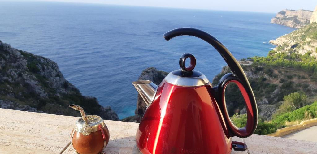 a red tea kettle sitting on a table overlooking the ocean at la ventana al mar in Jávea