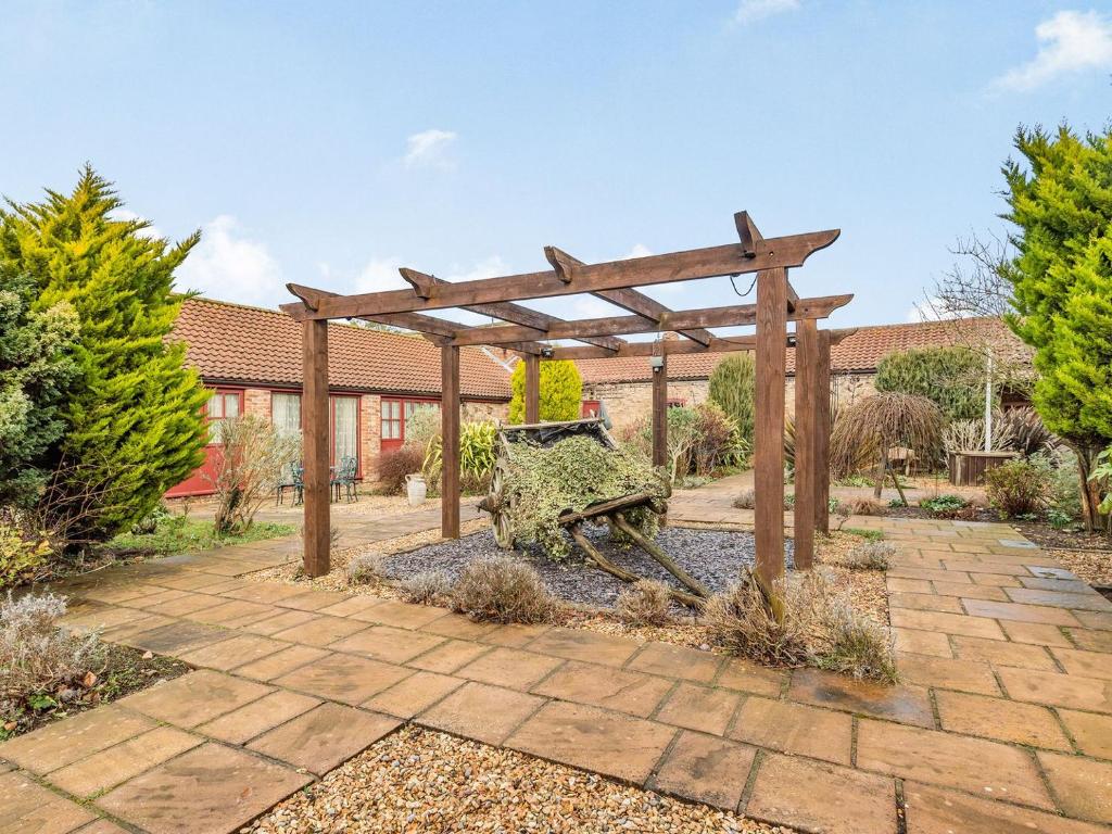 a wooden pergola with a bench in a garden at The Parlour - Uk37517 in Routh