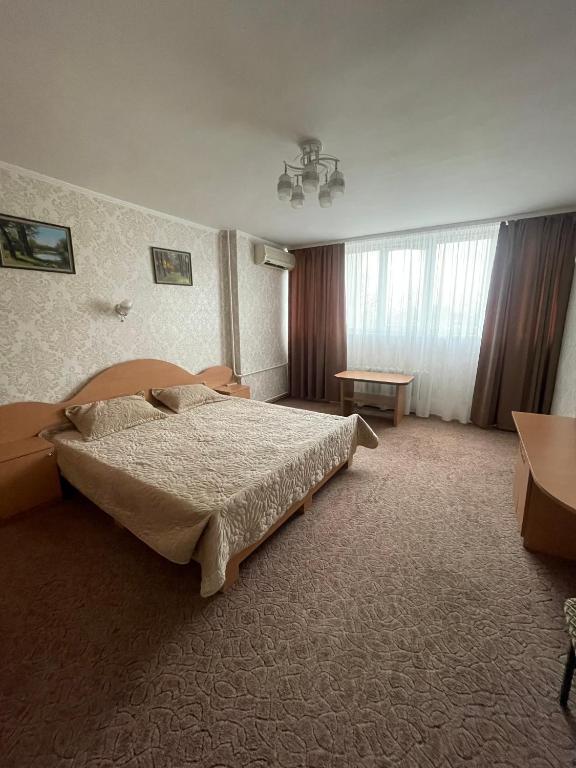 a bedroom with a large bed and a table at Zarea Hotel in Chişinău