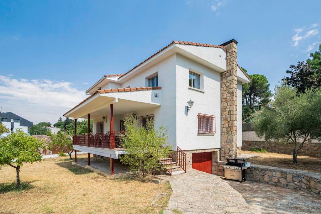 a white house with a porch and a yard at Casa Hortensia. Barbacoa en Robledo de Chavela in La Estación