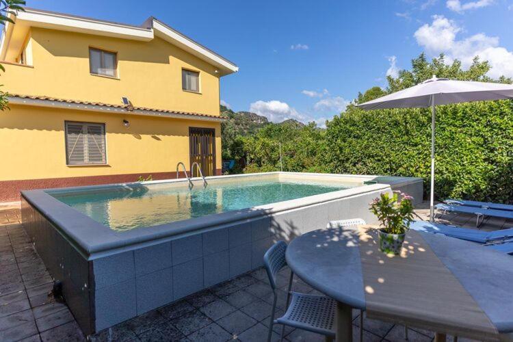 een zwembad met een tafel en een parasol bij Holiday home in Francavilla di Sicilia in Francavilla di Sicilia