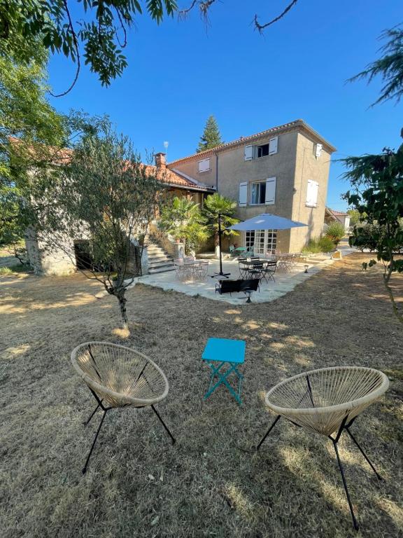 two chairs and a table in front of a building at Maison piscine Lot in Laburgade