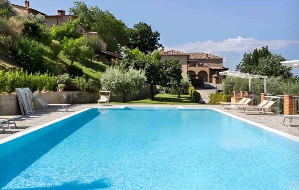 a swimming pool in a yard with chairs and a house at Agriturismo Casale Giulia in Volterra