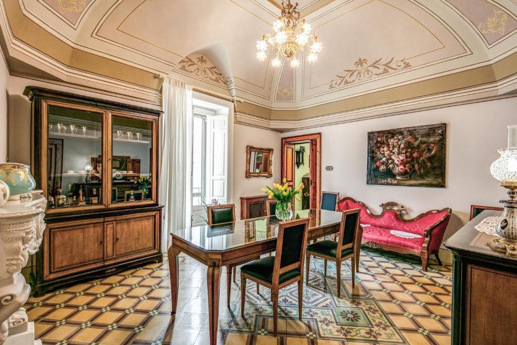 une salle à manger avec une table, des chaises et un lustre dans l'établissement Palazzo Stunis - Dimora di Charme, à Ostuni