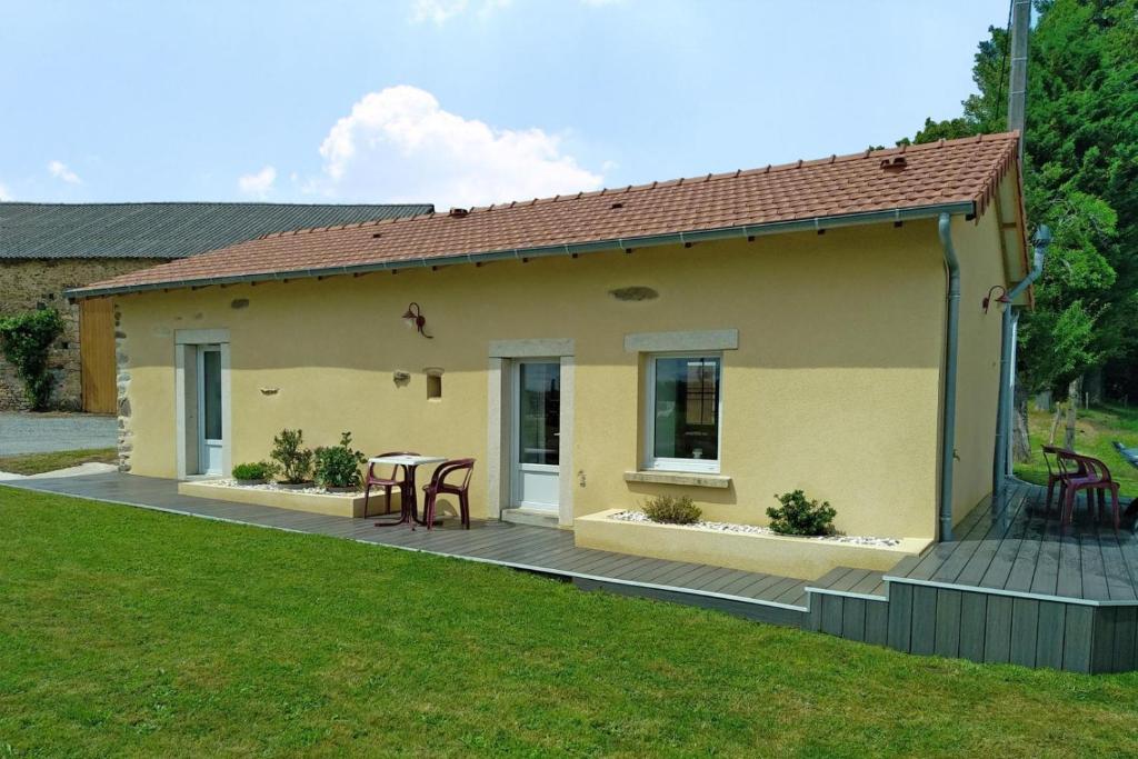 a small yellow house with a table on a deck at Gite des rousses in Saint-Laurent-les-Églises