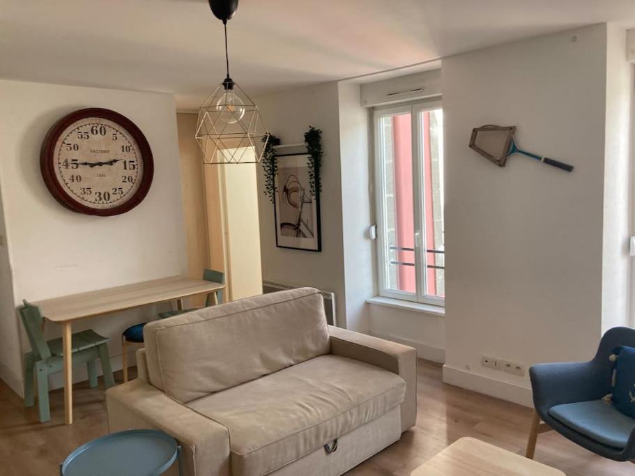 a living room with a couch and a clock on the wall at Appartement 1 chambre proximité Port de commerce et Gare SNCF in Brest