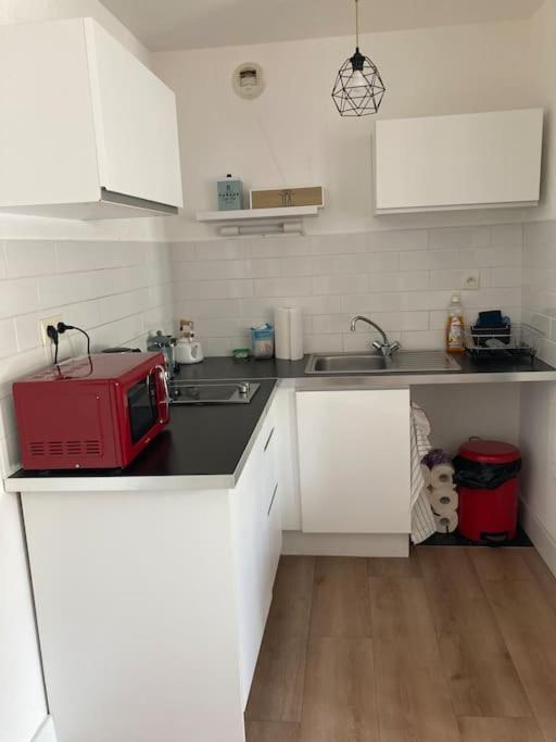 a kitchen with white cabinets and a red microwave at Appartement 1 chambre proximité Port de commerce et Gare SNCF in Brest