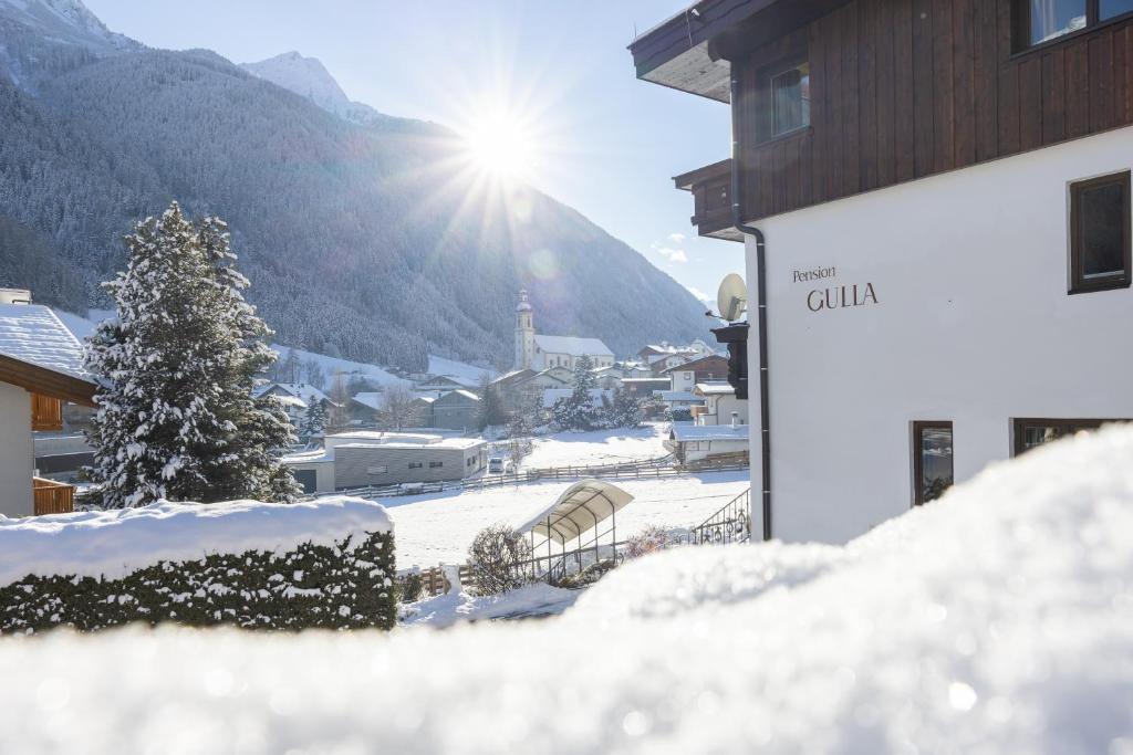 a town covered in snow with the sun in the background at Pension Gulla - Ferienhaus Appartements B&B in Neustift im Stubaital