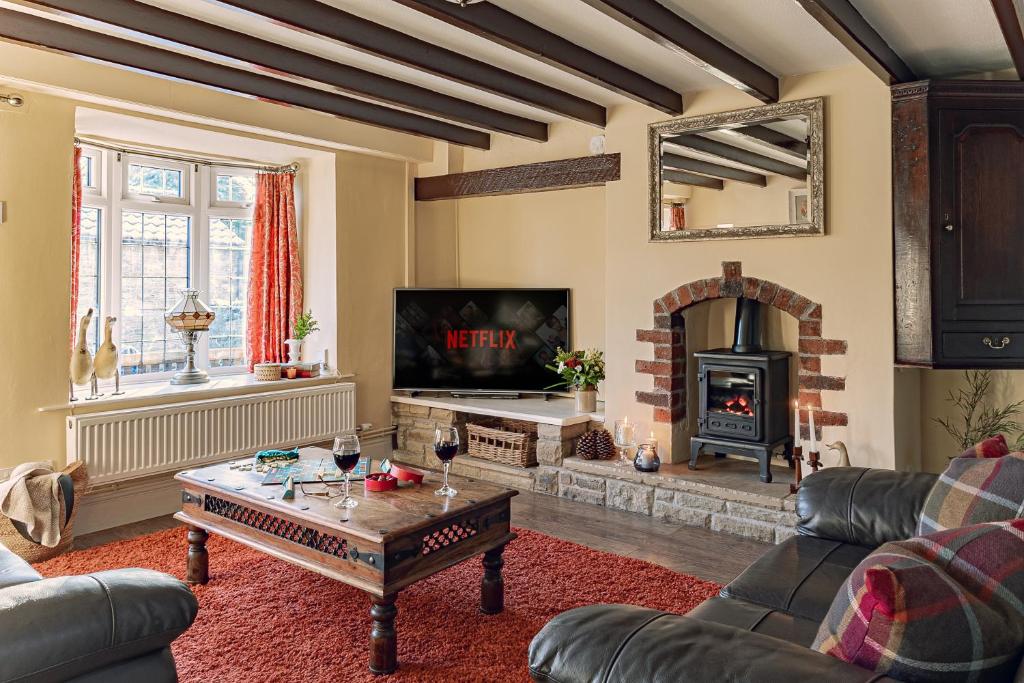 a living room with a fireplace and a table at Garth Cottage in West Ayton in Scarborough