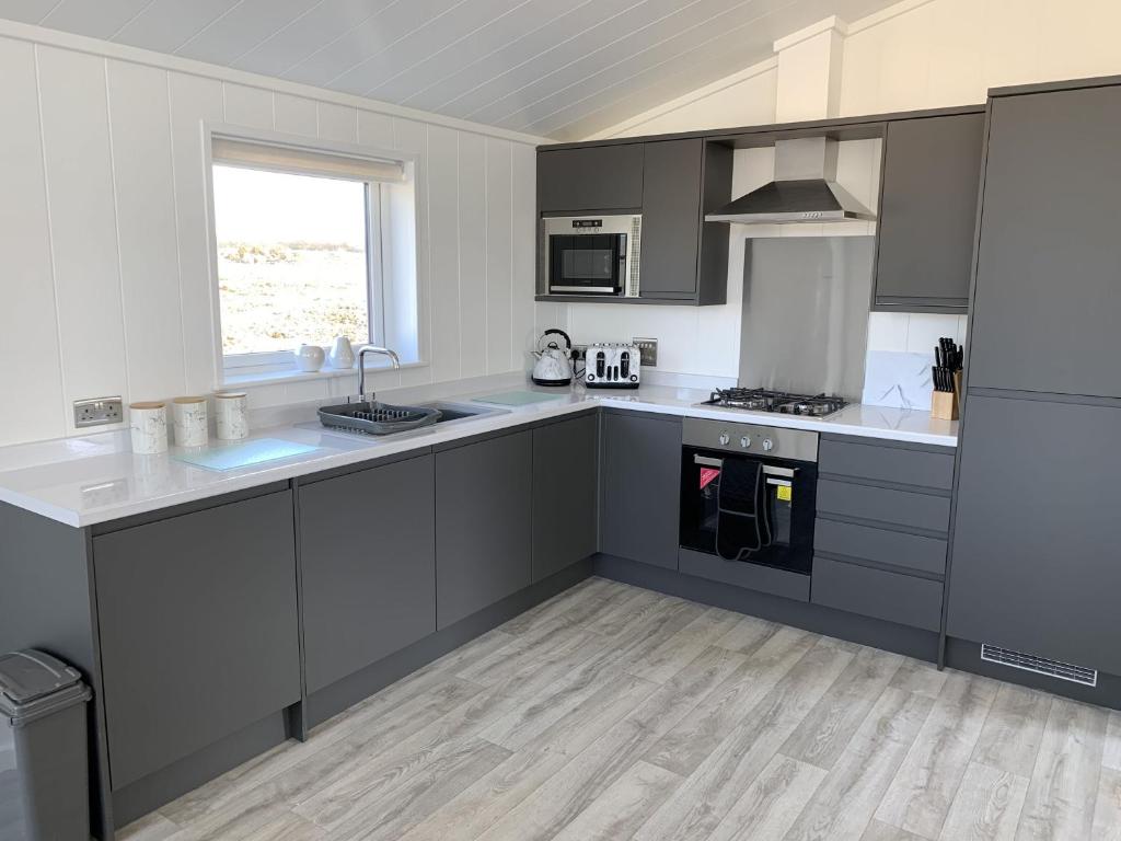 a kitchen with gray and white cabinets and a sink at Cherry Blossom 42 Hot Tub in Garton