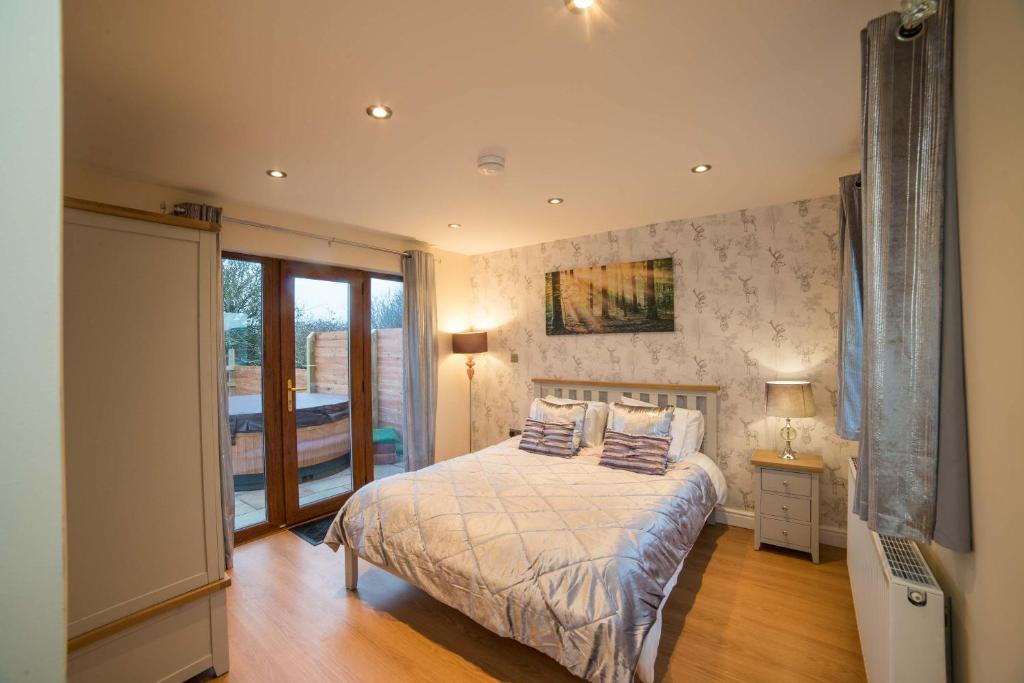 a bedroom with a bed and a glass door at Hawthorn 19 Hot Tub in Garton