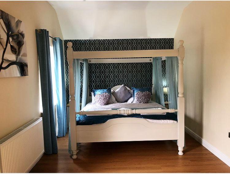 a canopy bed with blue pillows on it in a room at Maple 20 Hot Tub in Garton