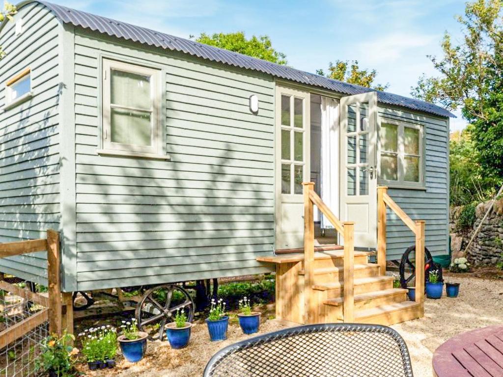 a tiny house with a staircase and a patio at Fig Tree Shepherds Hut in Bridport