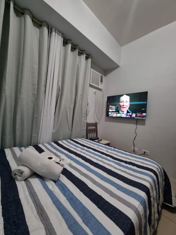 a bedroom with a bed with a television in it at Macks Awesome Place 204 NetflixFastWifi in Manila