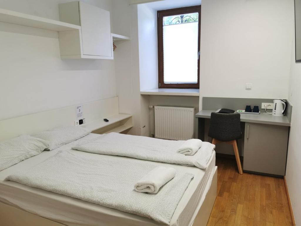 two beds in a room with a kitchen and a desk at Rooms Sincere 1830 in Ljubljana