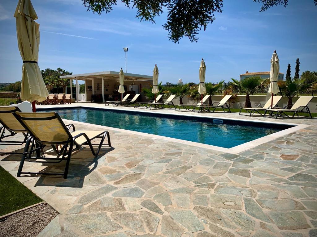 Villa Hylas Luxury Bed & Breakfast Kilada في Kilada: مسبح مع كراسي صالة ومظلة
