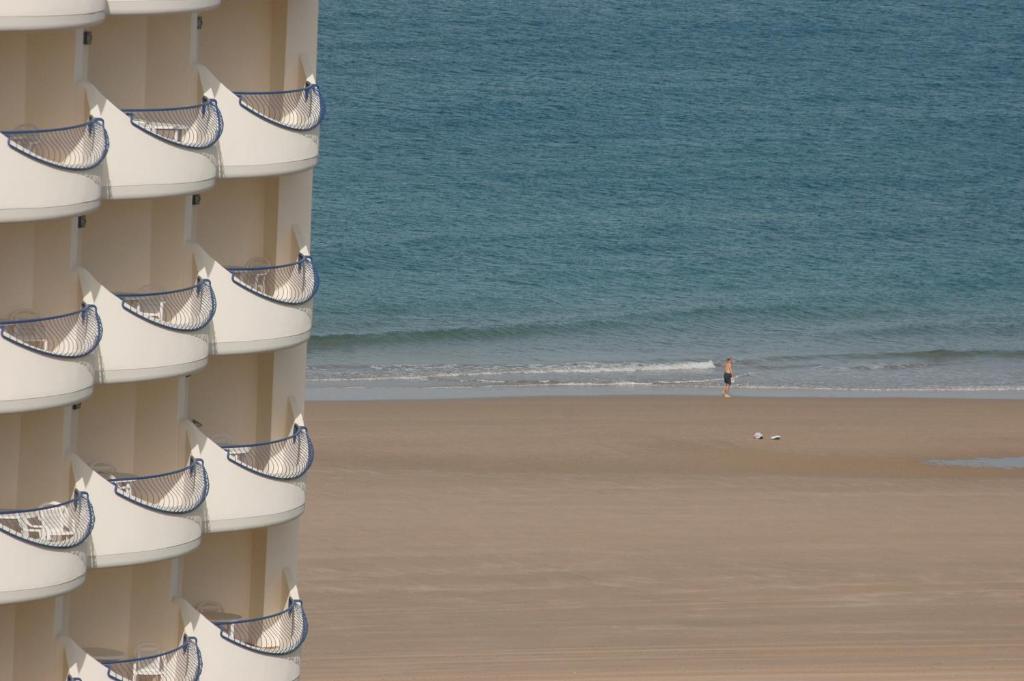 a person standing on the beach in front of the ocean at Hotel Playa Victoria in Cádiz