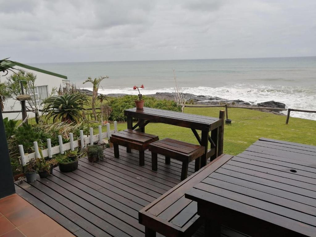 eine Terrasse mit einem Picknicktisch und Bänken am Strand in der Unterkunft Mazeppa Sunrise Beach Accommodation in Mazeppa Bay