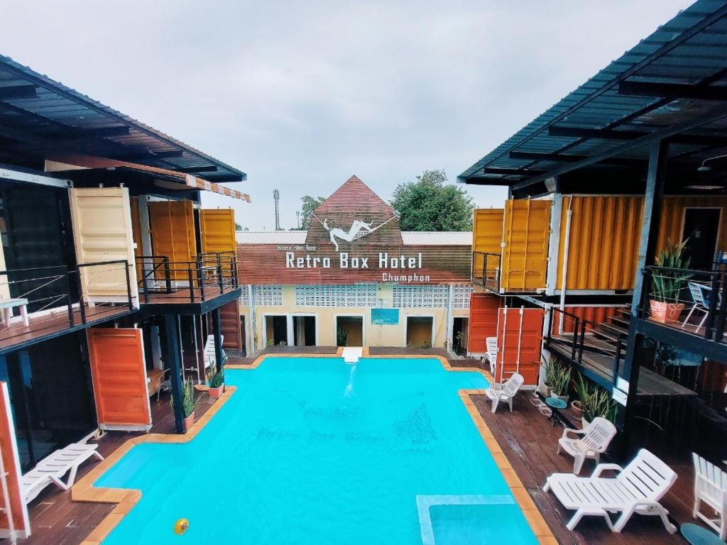 a large swimming pool with chairs and a hotel at Retro Box Hotel Chumphon in Chumphon