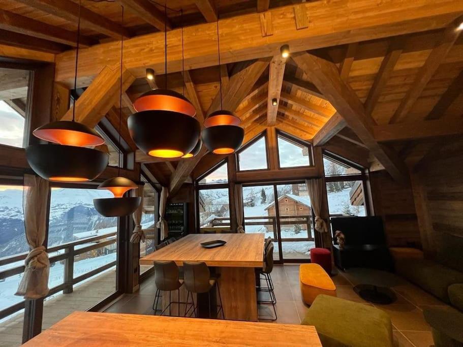 Cette grande chambre dispose d'une table et de fenêtres. dans l'établissement Magnifique chalet sur les pistes, le Paradis c'est ici !, à La Toussuire