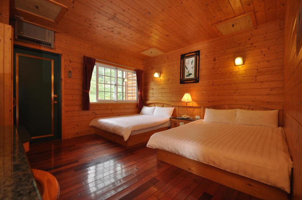 a bedroom with two beds in a wooden cabin at Kingtaiwan Hotel in Lugu Lake