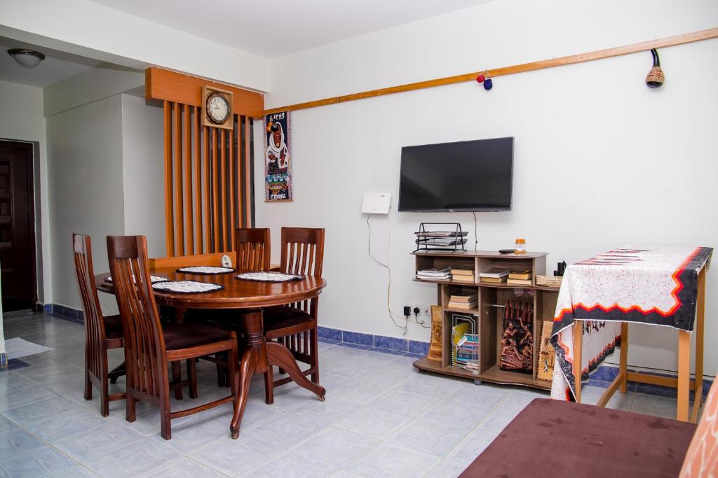 a dining room with a table and chairs and a television at Nairobi Airport Apartments in Syokimau
