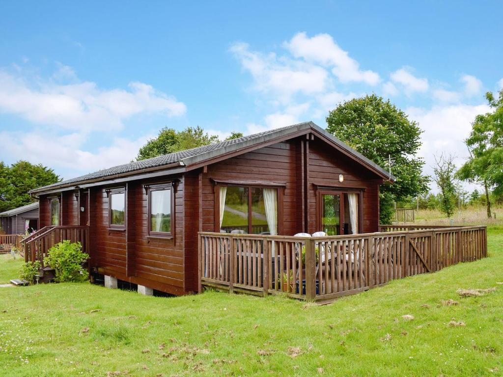 a wooden cabin with a large deck in a field at The Shed in Woolfardisworthy