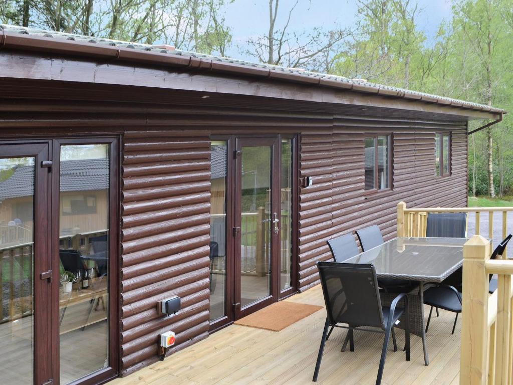 Cabaña de madera con mesa y sillas en una terraza en Reivers Rest en Otterburn