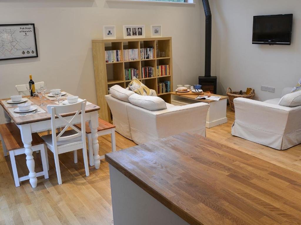 uma sala de estar com mobiliário branco e uma mesa em Blyth Green Stable em Long Stratton