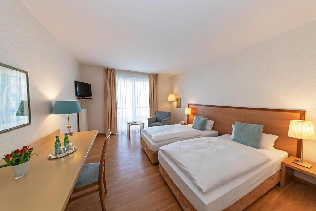 een hotelkamer met 2 bedden en een bureau bij Thiesmann´s Hotel & Restaurant in Mülheim an der Ruhr