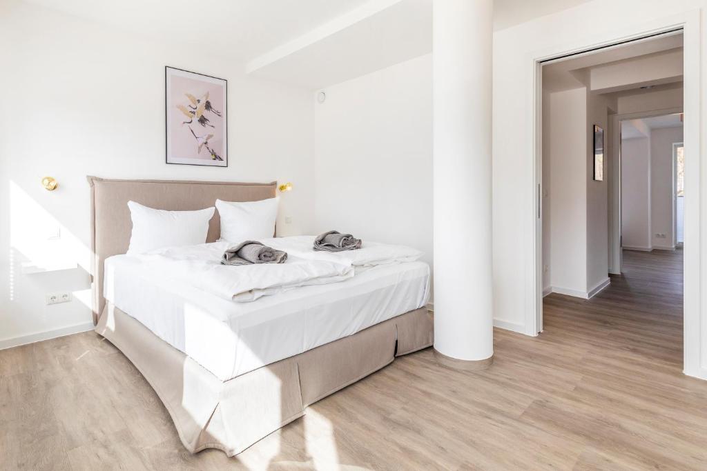 ein weißes Schlafzimmer mit einem großen Bett mit weißer Bettwäsche in der Unterkunft Ferienwohnung Sonnenschein Haus Hiddensee Prora in Binz