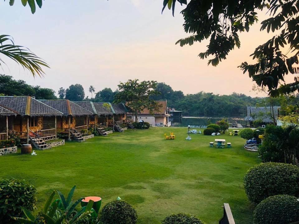 a large yard with houses and a large grass field at Bamboo House Resort in Kanchanaburi City