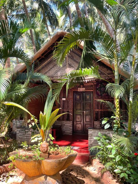 a wooden house with palm trees in front of it at Palm Trees Ayurvedic Heritage in Patnem