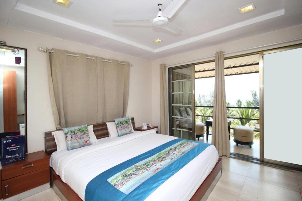 a bedroom with a large bed and a balcony at Sea Breeze Beach Resort Murud in Murud