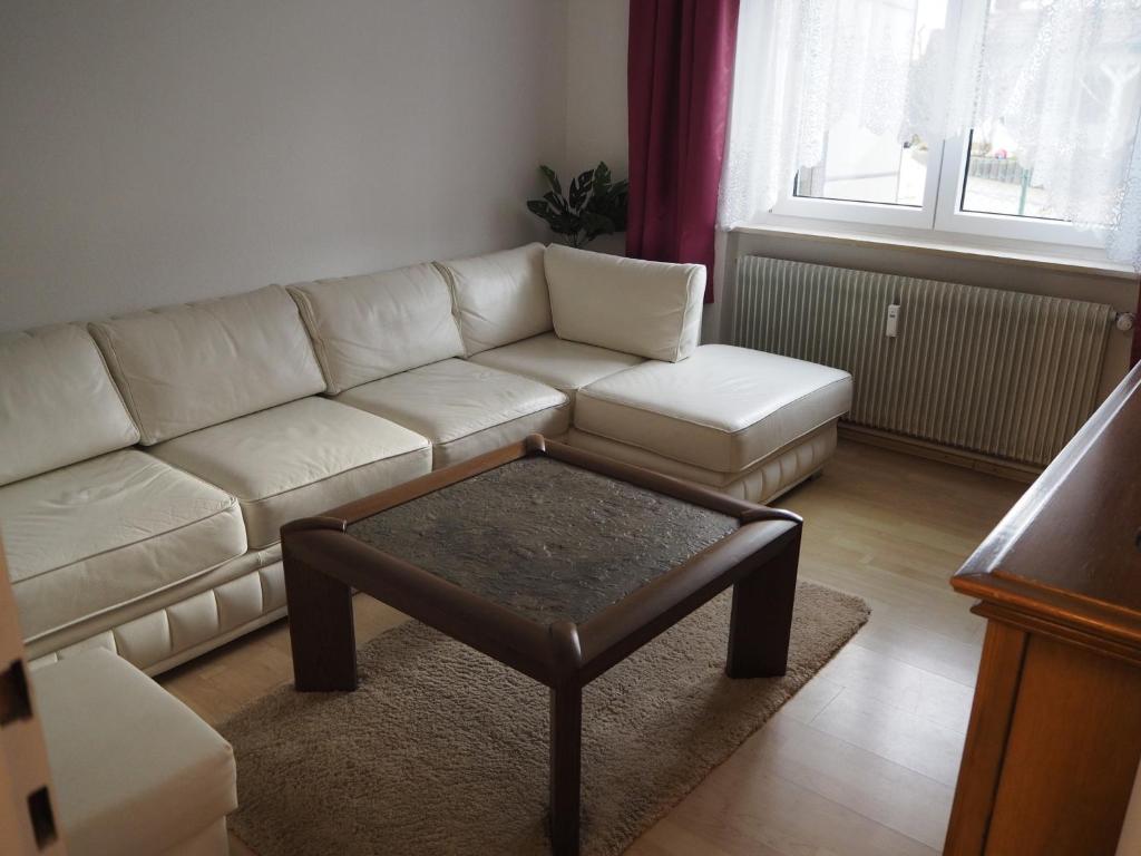 a living room with a white couch and a coffee table at Ferienwohnung Schlossblick in Amtzell