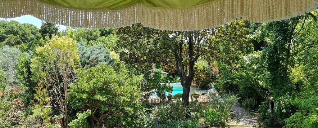 a canopy over a garden with trees and a lake at Villa Aigarden maison d'hôtes in Avignon