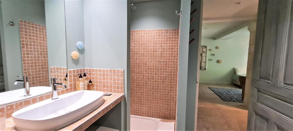a bathroom with a white sink and a brick wall at Villa Aigarden maison d'hôtes in Avignon