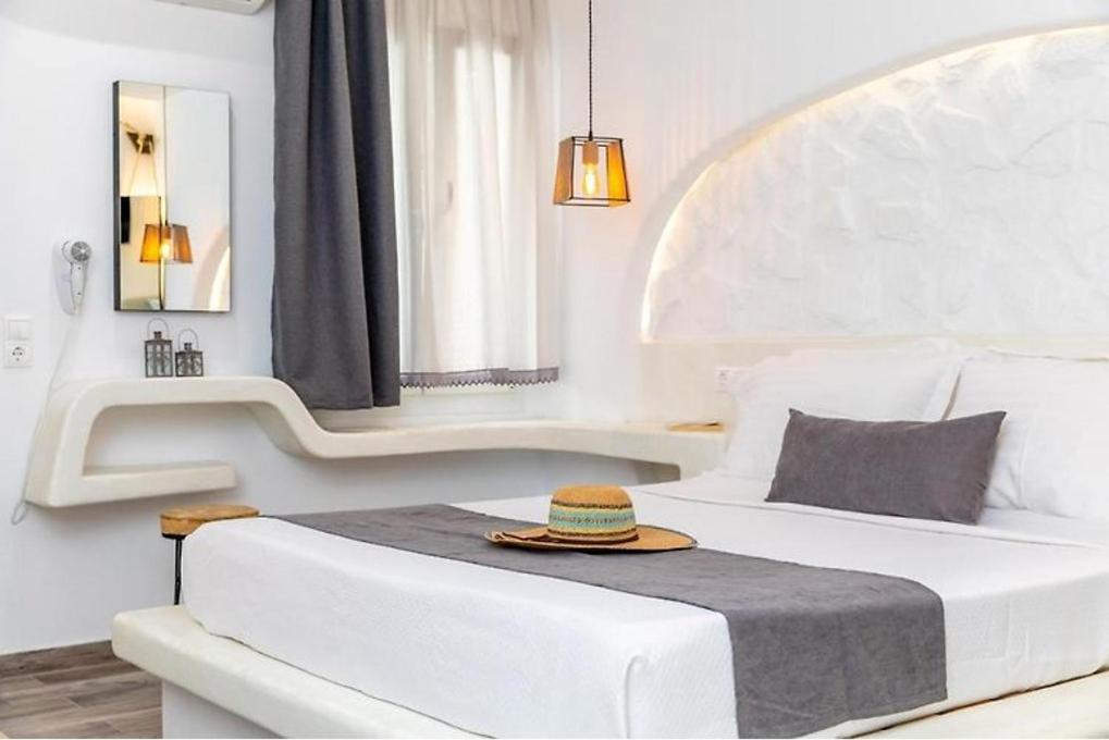 a white bedroom with a bed with a hat on it at Blue Heart Luxury Suites in Naxos Chora