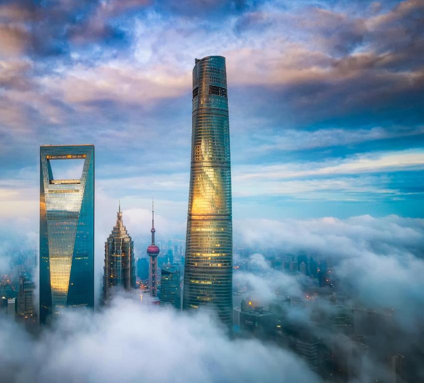 un groupe de grands bâtiments dans le ciel au-dessus des nuages dans l'établissement J Hotel, Shanghai Tower - Above All Else, Overlooking the Bund, à Shanghai