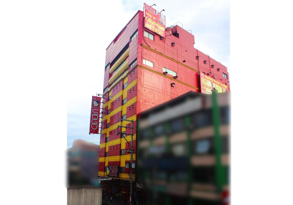a tall red building with lots of signs on it at Hotel Sogo Edsa Cubao in Manila
