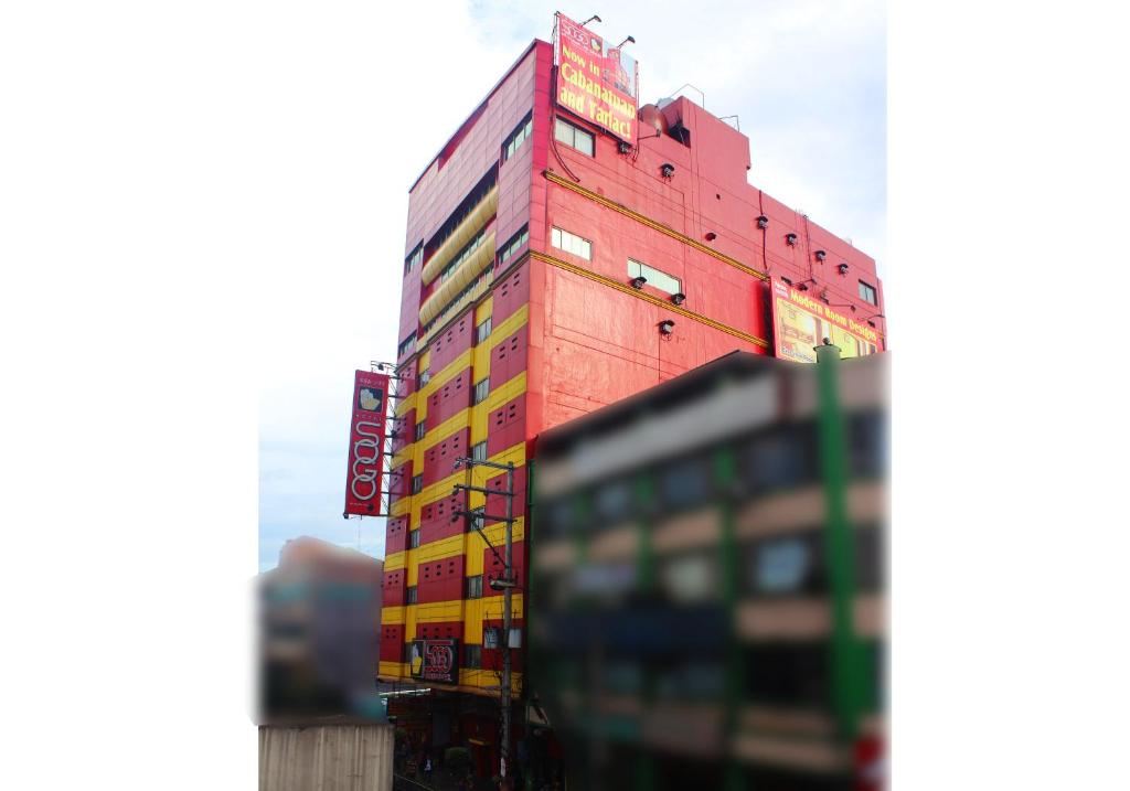 um edifício alto e vermelho com muitos sinais. em Hotel Sogo Edsa Cubao em Manila