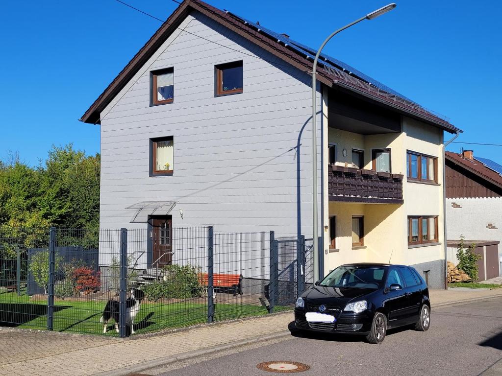 a black car parked in front of a white house at Ferienwohnung am Pingenpfad in Merchweiler