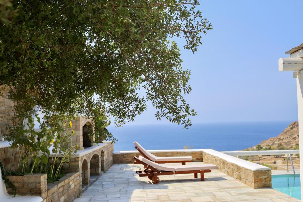 un par de bancos sentados junto a una piscina en Villa Giulia, seaview villa en Ios Chora