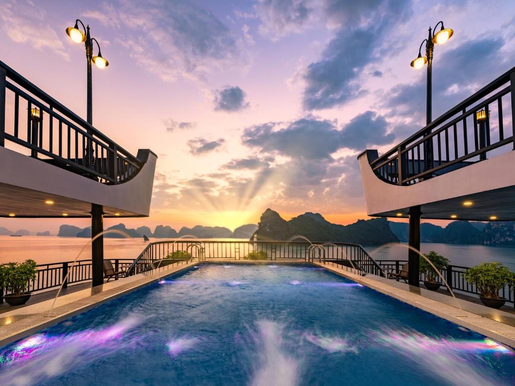 ein Pool auf dem Dach eines Resorts mit Sonnenuntergang in der Unterkunft Rita Cruise in Hạ Long