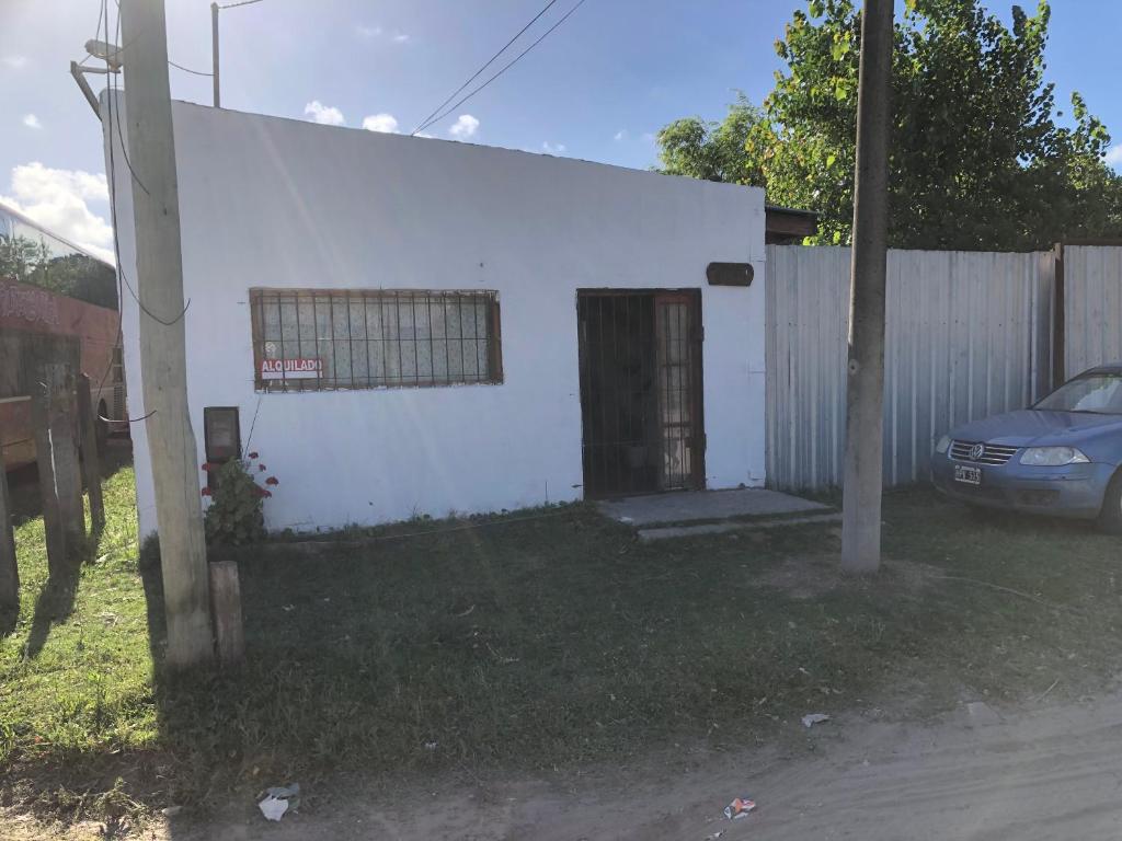 una pequeña casa blanca con una valla y un coche en Alberto en Mar de Ajó