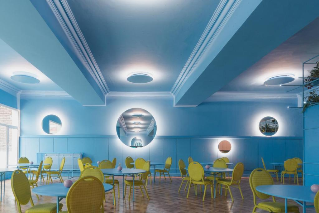 a dining room with blue ceilings and tables and yellow chairs at Selina Montevideo in Montevideo