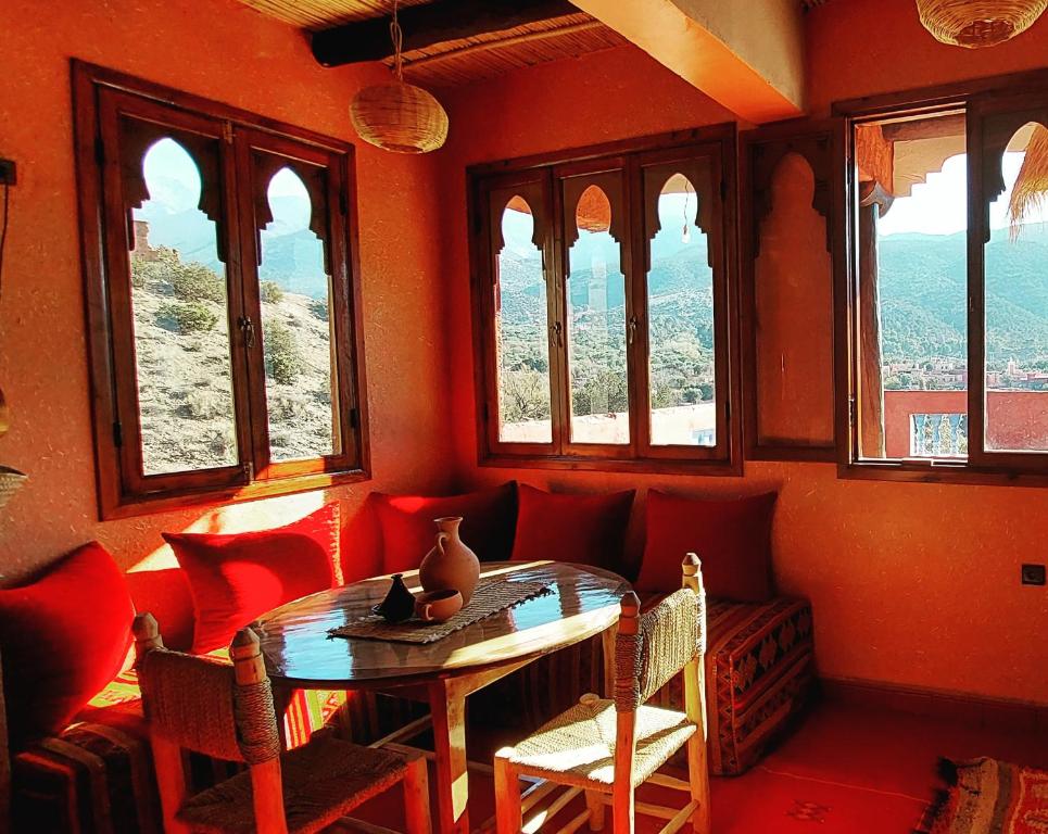 Cette chambre comprend une table, des chaises et des fenêtres. dans l'établissement Ouirgane discovery lodge, à Ouirgane