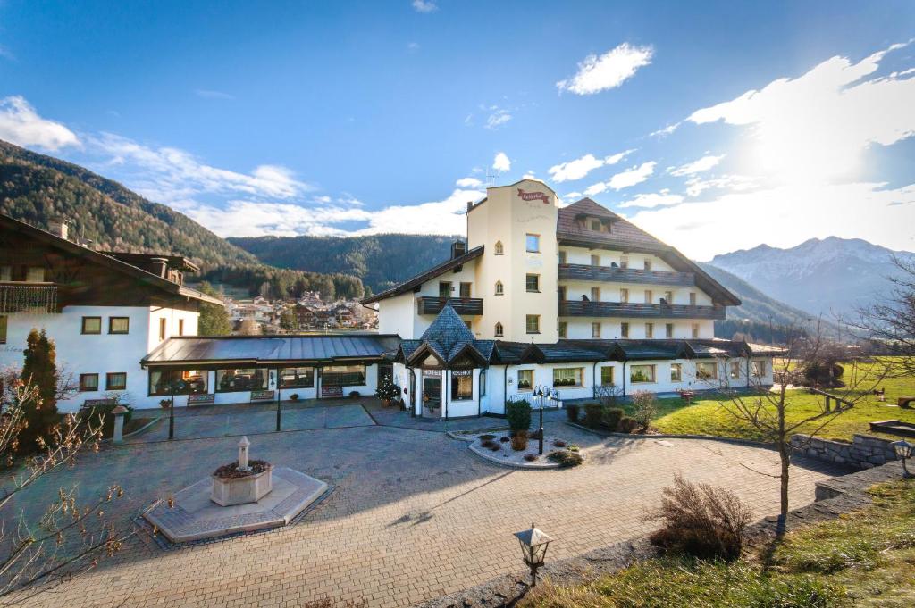 a large building with a courtyard and mountains in the background at Smy Koflerhof Wellness & Spa Dolomiti in Rasun di Sopra