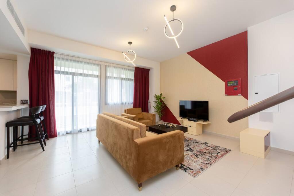 uma sala de estar com um sofá e uma televisão em Stunning 3 bedroom townhouse in Townsquare em Dubai